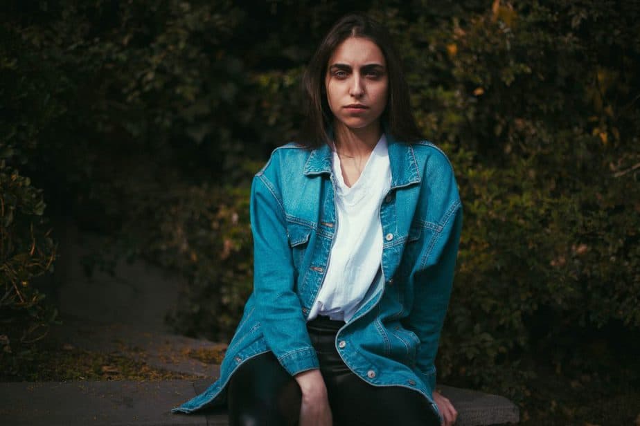 girl in a blue shirt with white t-shirt sitting in a rock looking stoic