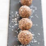 Peanut butter balls on a slate with coconut shavings