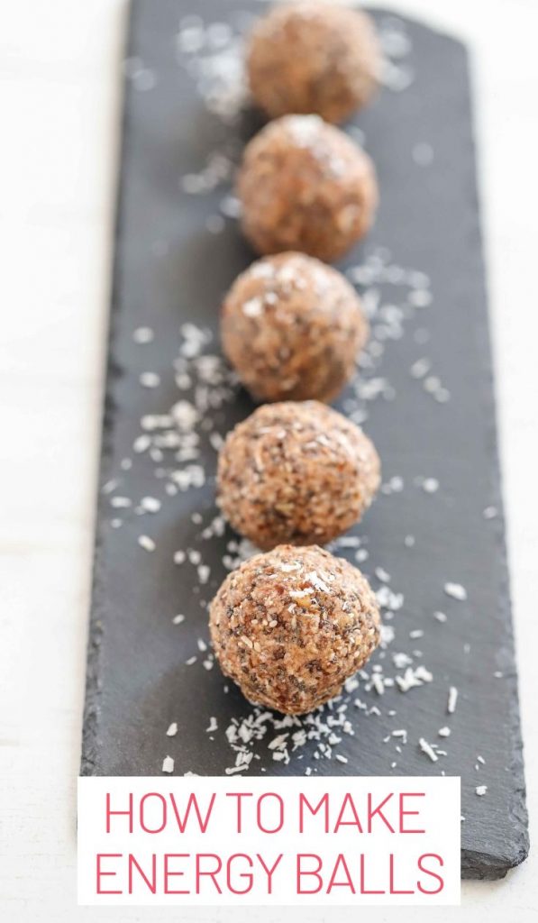 How to make protein balls. Focus is on one protein ball on a slate with coconut shaving surrounding it.