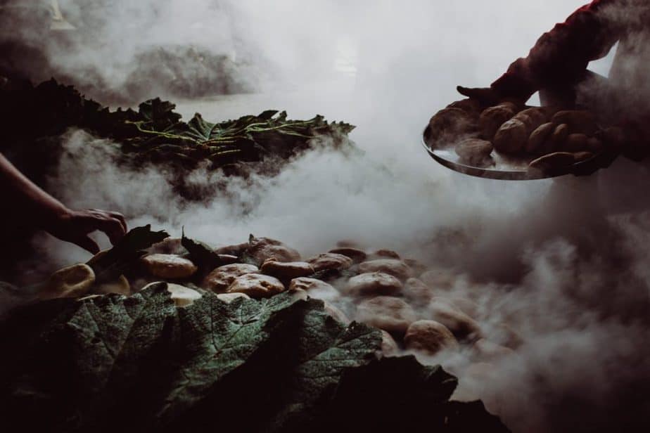 Steam rocks and a man holding a plate with hot rocks on it.