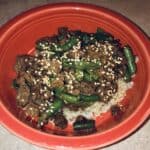 beef and green beans over brown rice, in an orange bowl