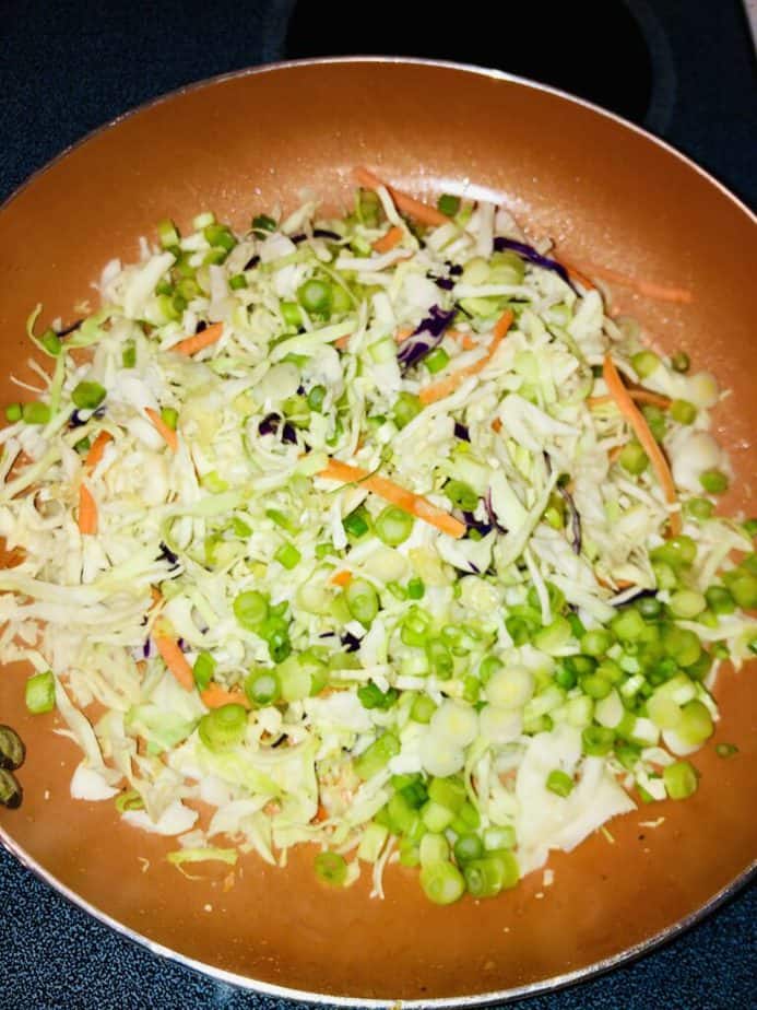 Copper pan with a shredded cabbage mix and scallions. 