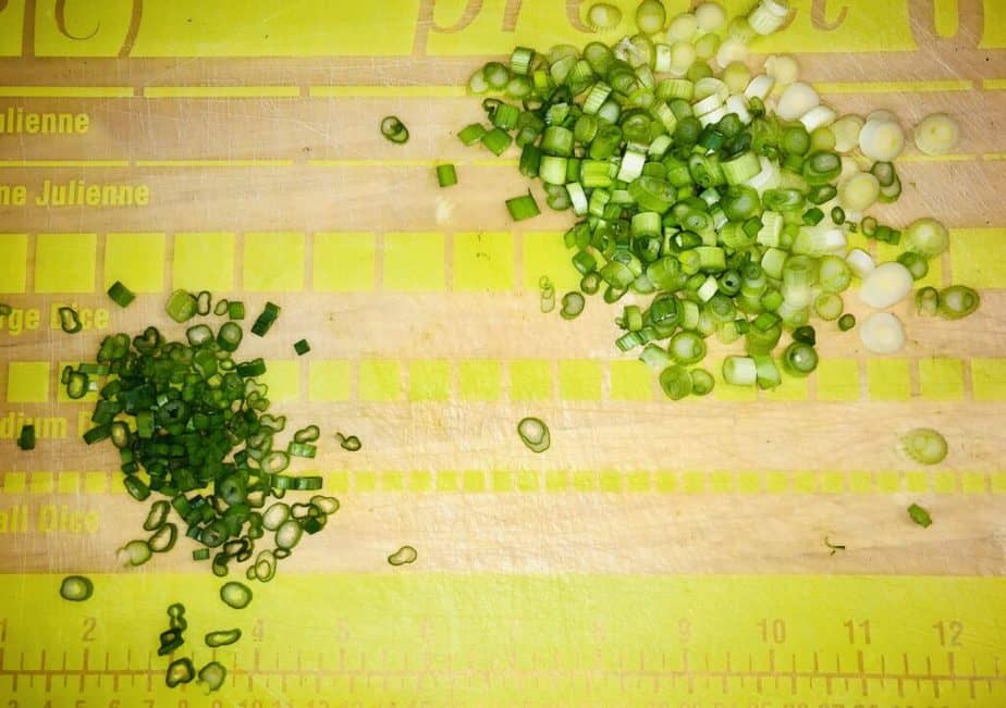 Green and clear cutting board with chopped scallions on it. 