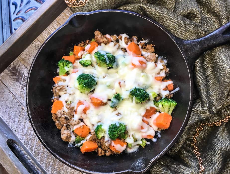 turkey sausage with sweet potatoes and broccoli in a cast iron skillet with melted mozzarella cheese