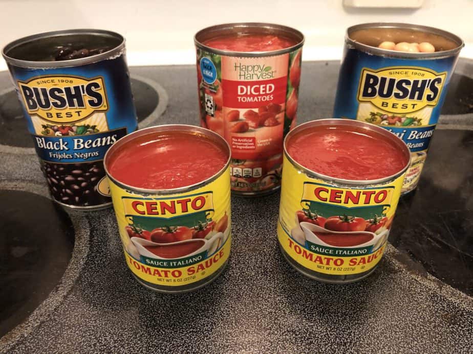 Open can of black beans, open can of cannellini beans, open can of diced tomatoes, two open cans of tomato sauce 