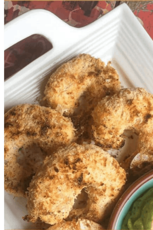 Four pieces of coconut shrimp on a white plate with a handle