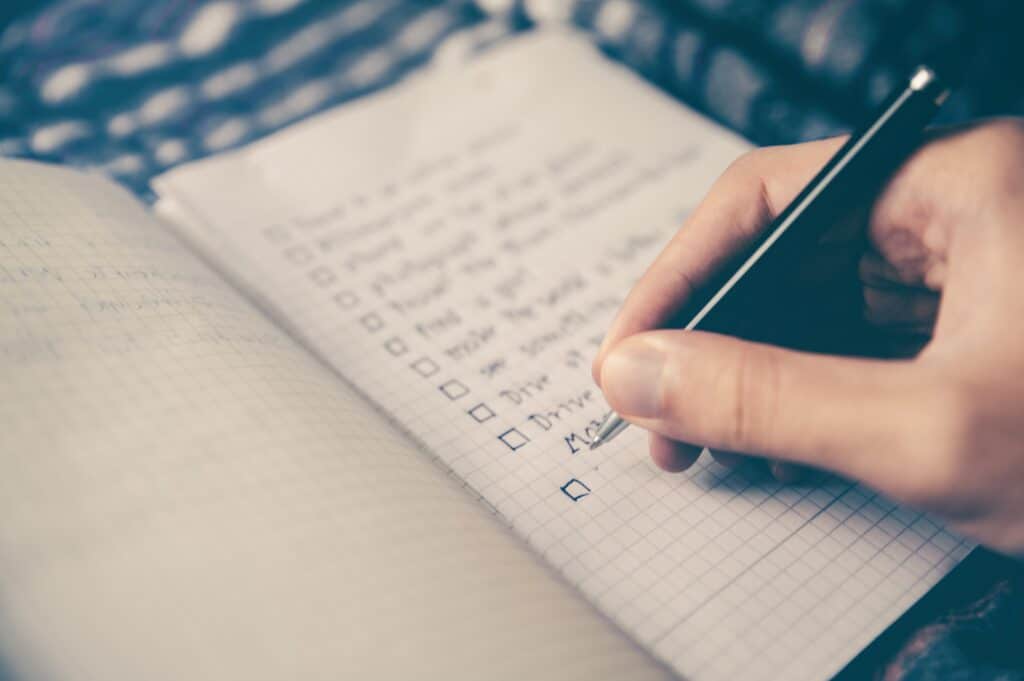 appreciation list, hand using a black ink pen making a list on a notebook 