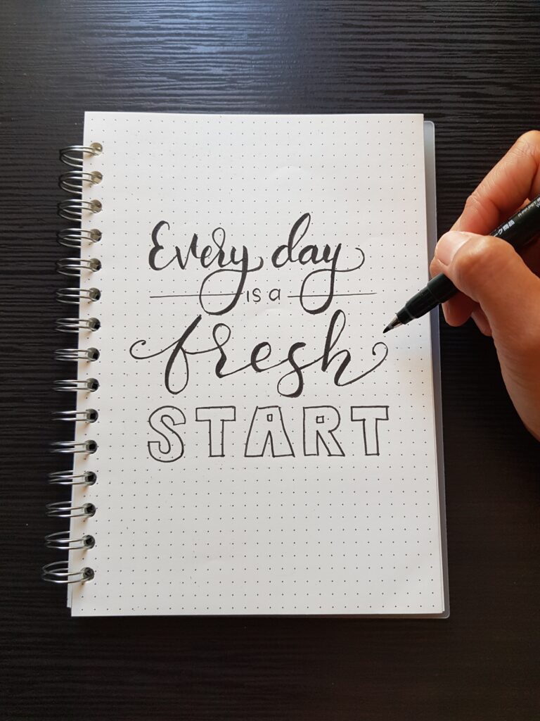 Every day is a fresh start written on a notebook in cursive.