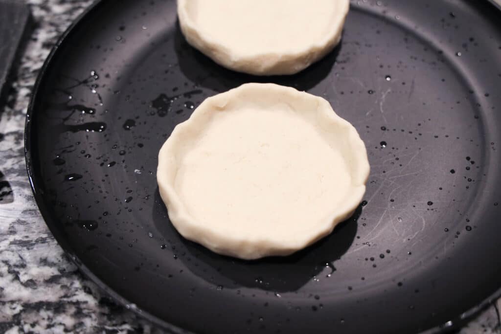 Sope uncooked on a black plate on a counter.