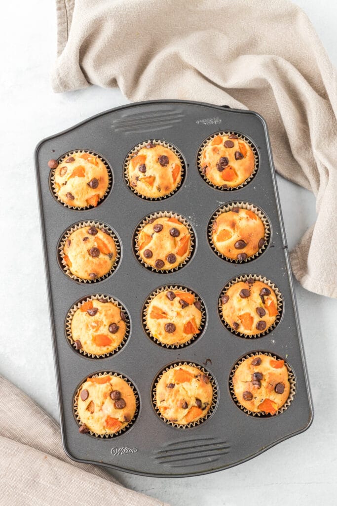 orange breakfast muffins ina muffin pan on a white table