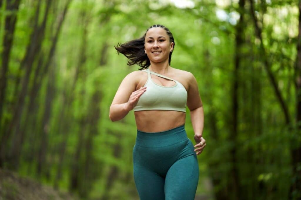 Woman smiling while running through forest