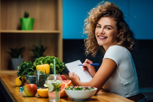 Nutritionist working in office. Doctor writing diet plan on table and using vegetables. Sport trainer. Lifestyle.