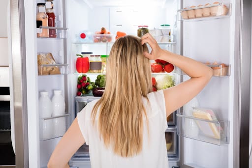 Young lady opened the fridge and, in frustration.