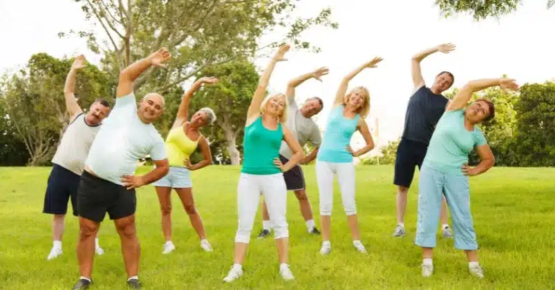 A group of people in the grass stretching and getting ready to do some Low impact exercises